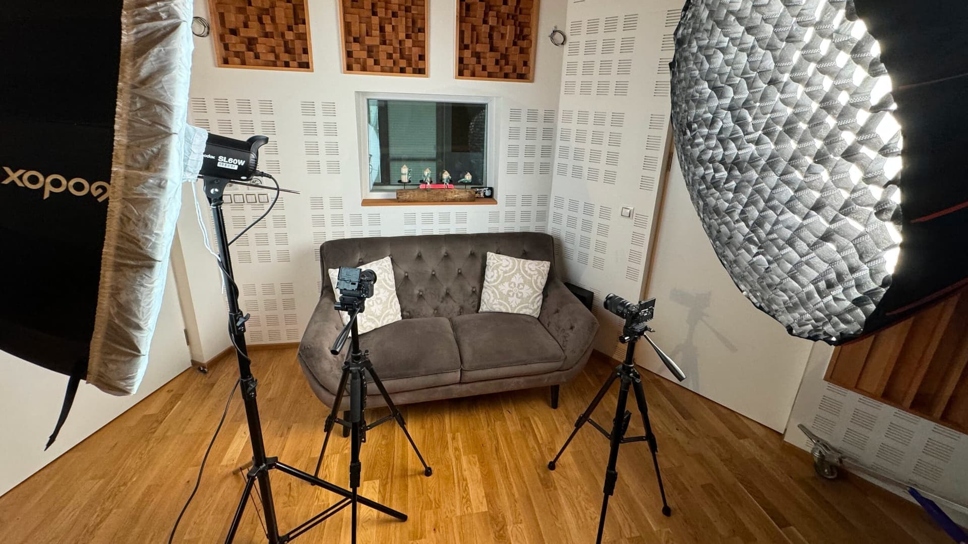 Podcast set with a sofa, tripod cameras, and softbox lighting
